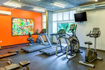 a room filled with cardio equipment and a flat screen tv at The Parker Apartments, Portland, OR, 97209